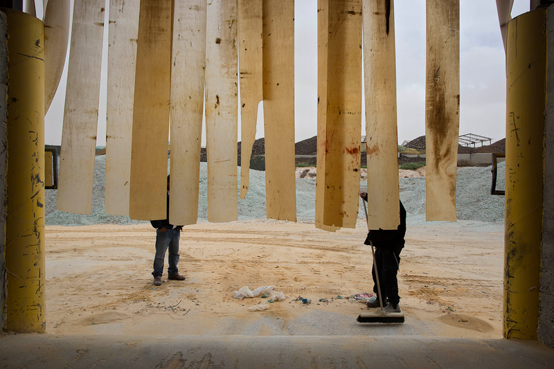 A worker sweeps sand used to manufacture glass bottles.